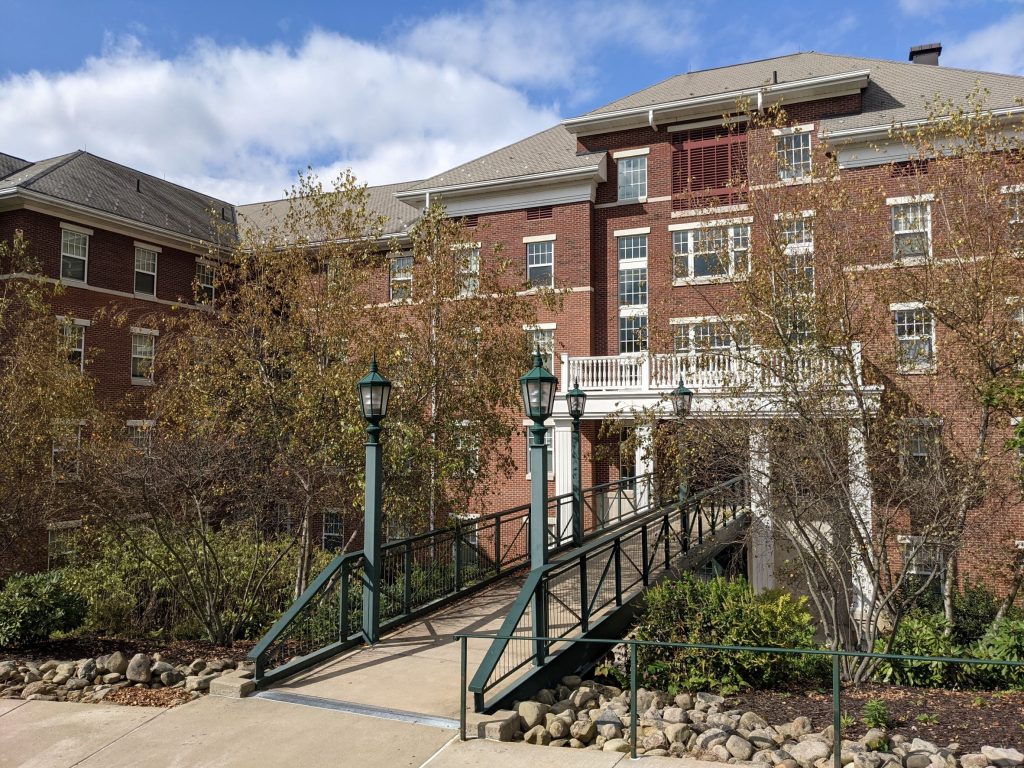 Modern Georgian Style red brick with white accent residence hall with green bridge leading to front door in Meadville, Pennsylvania
