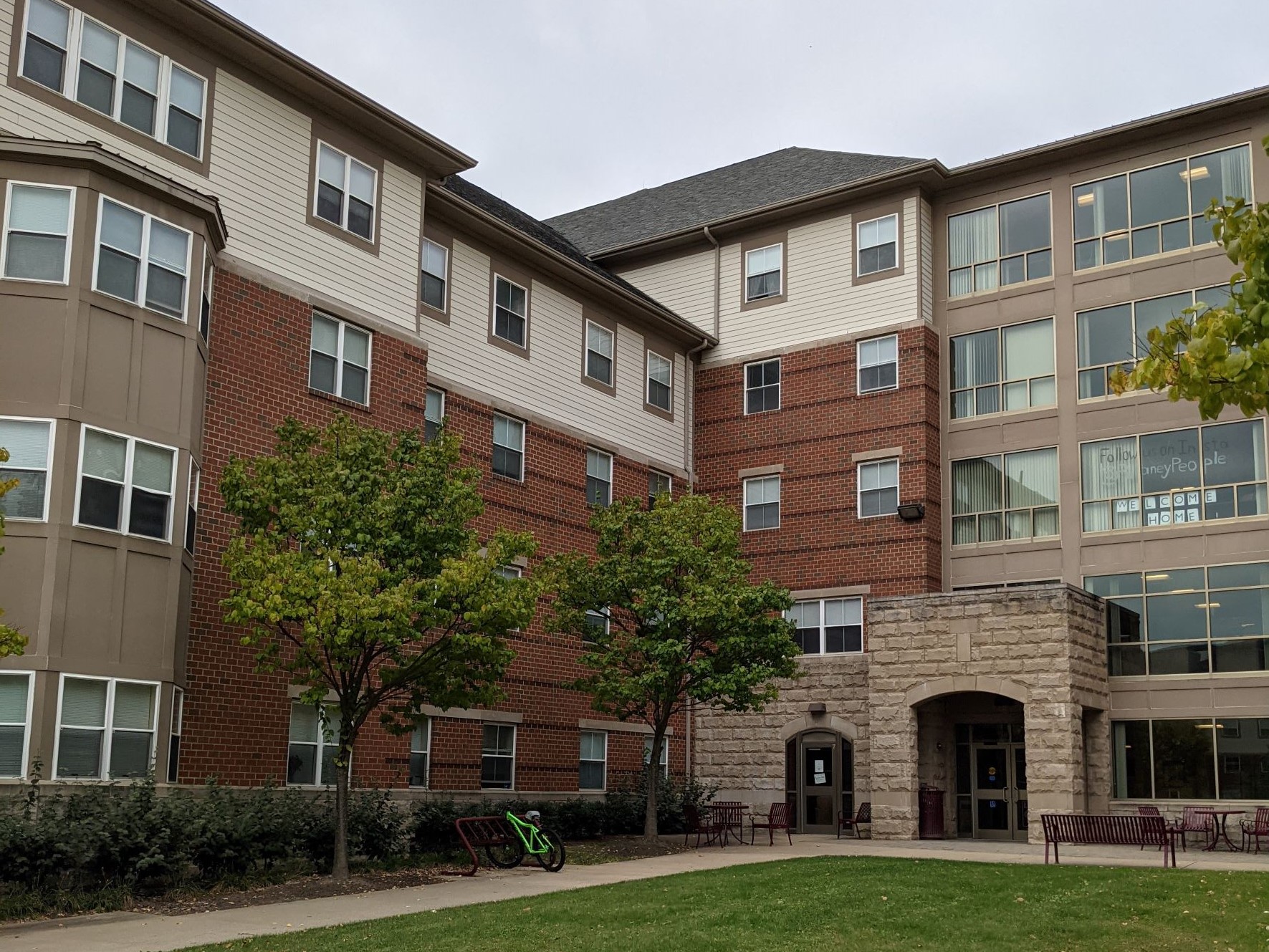 Traditional looking red brick contemporary living learning student housing community dormitory building with tan clerestory , courtyard in foreground, stone brick portico at building entry