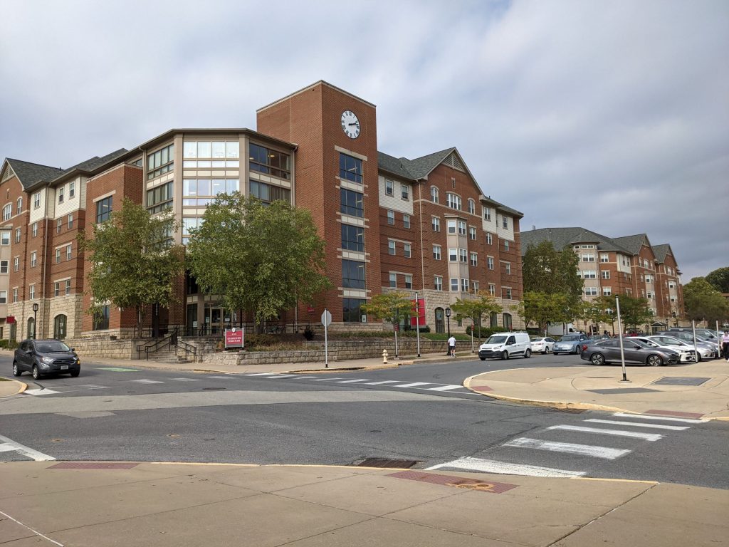 red brick residential looking residence halls with glass corner, stone base, and large clocktower overlooking streetcorner outside of Pittsburgh Pennsylvania