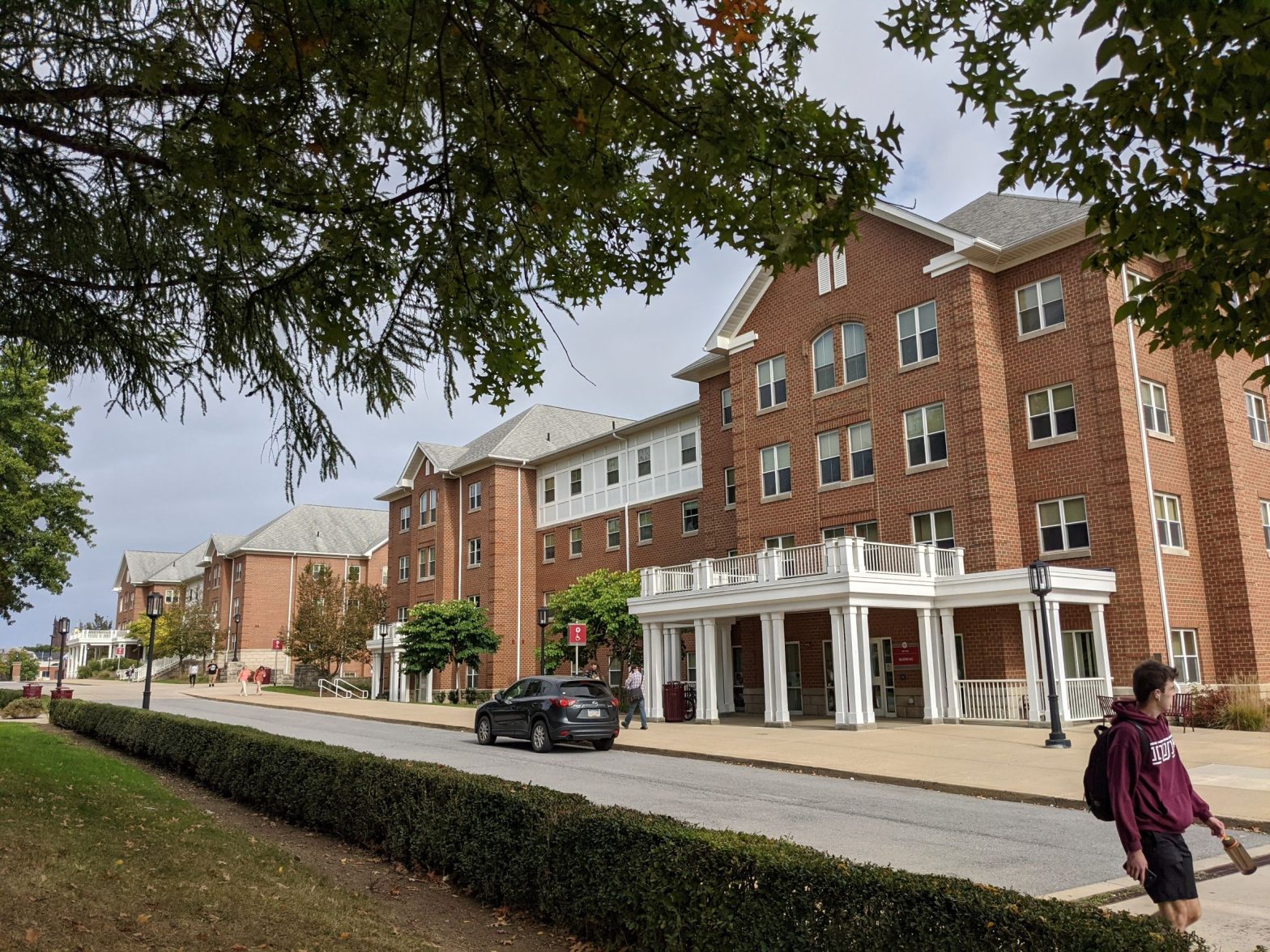 Historical looking pink brick residence hall with many gabled roofs, white front porch and trim, truncated dormer windows and brick quoining, very classical looking building (designed in style of Sutton Hall, the old campus Main)