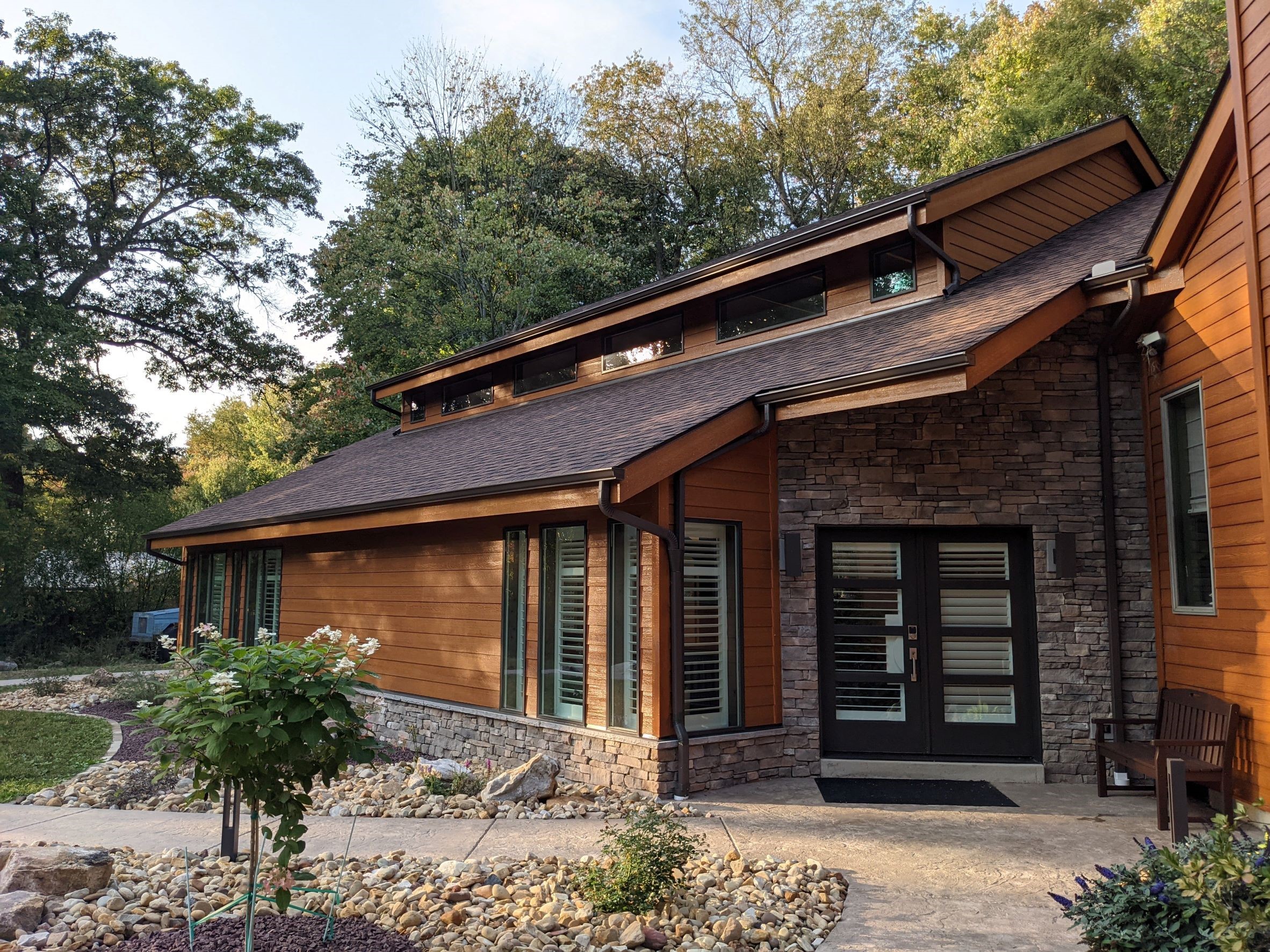 Exterior View of Contemporary House addition entrance with modern black doors in stone, surrounded by wood siding for an indoor pool outside of Pittsburgh Pennsylvania