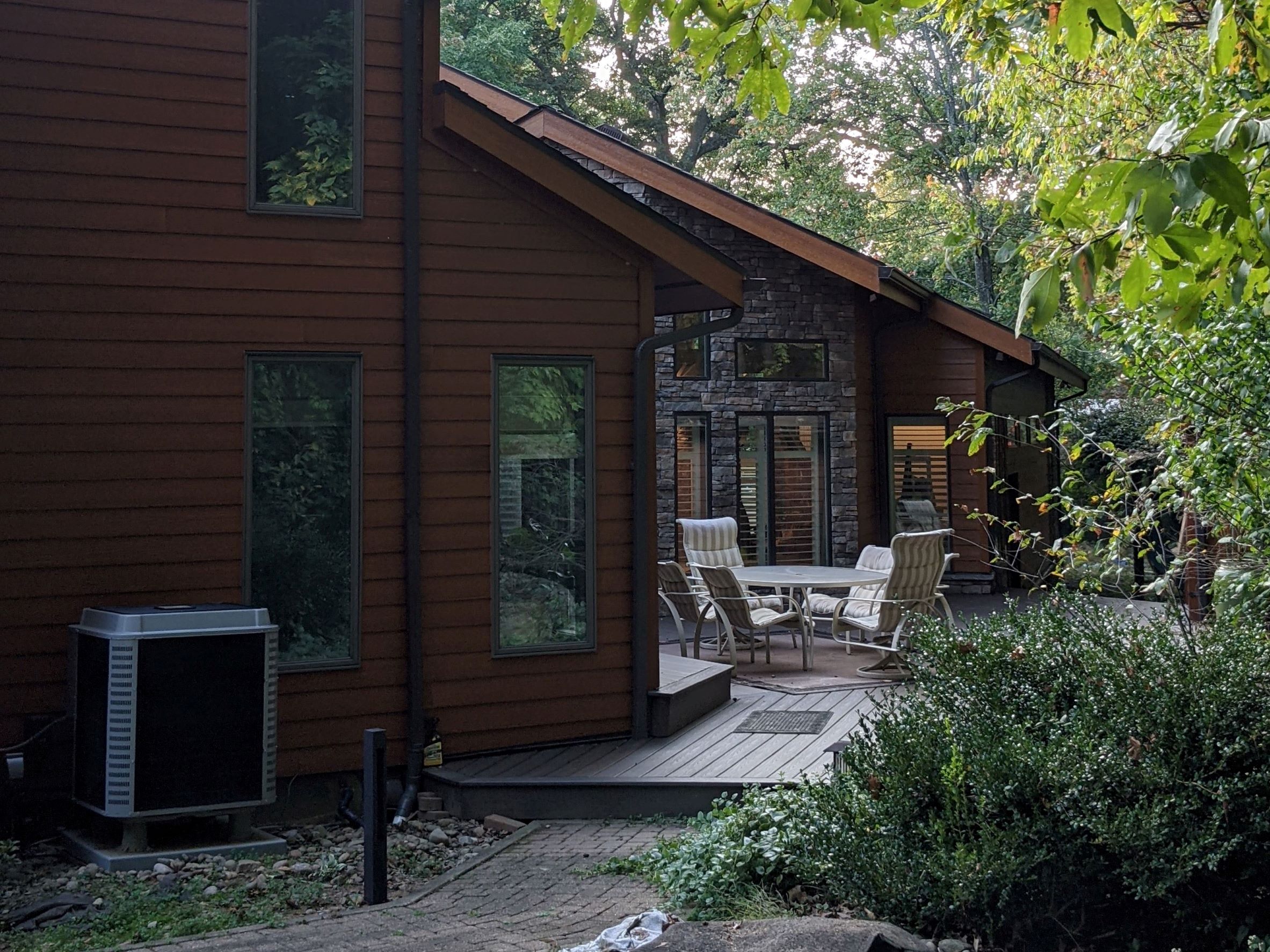 Isolated back porch with Contemporary House addition with stone, wood siding in the background, surrounded by trees and vegetation outside of Pittsburgh Pennsylvania