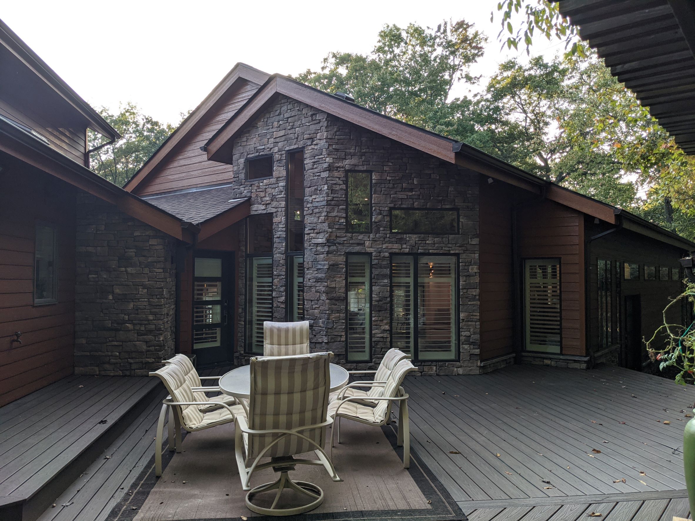 Stunning view of deck area in foreground with Contemporary House addition with stone, wood siding and modern geometric window design  outside of Pittsburgh Pennsylvania